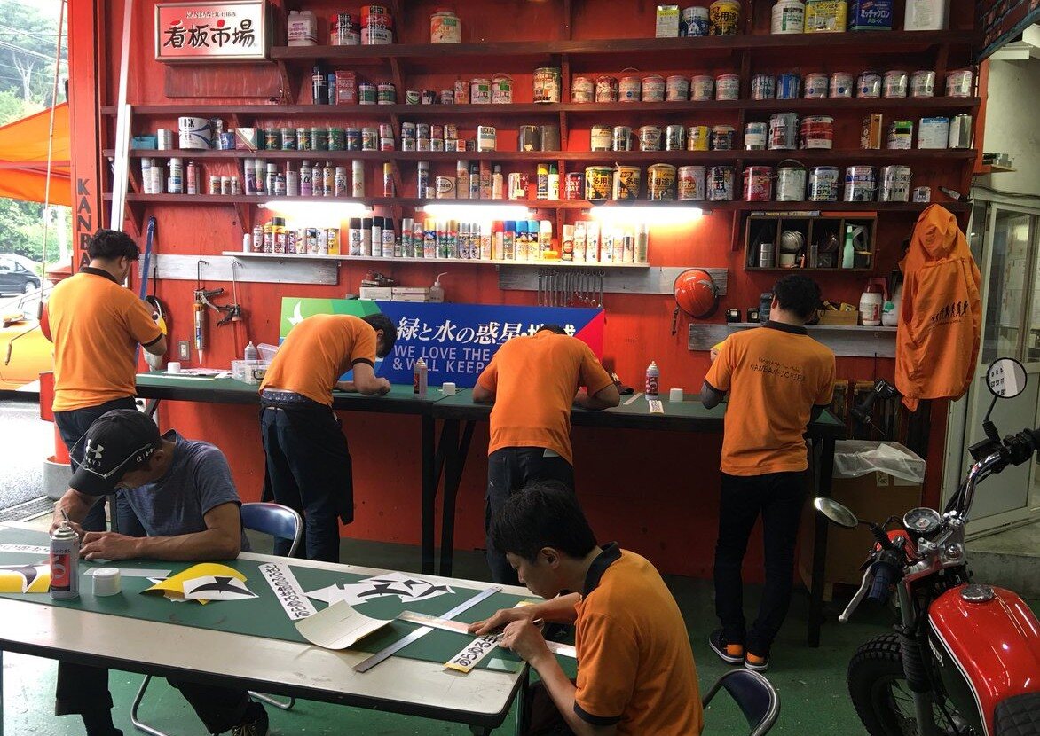 株式会社看板市場の工房でスタッフが協力して看板製作に取り組む様子